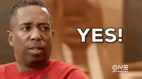 a man in a red shirt is making a face and saying yes .