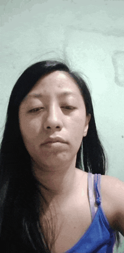 a woman in a blue tank top looks at the camera