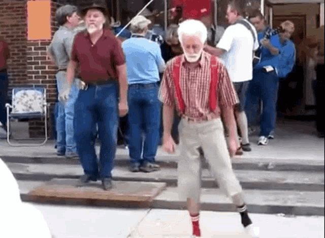 a man with a beard and suspenders is walking in front of a crowd of people