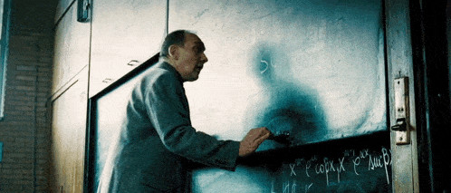a man is writing on a blackboard with the letters x and y