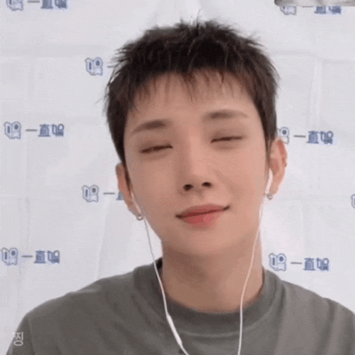 a young man wearing headphones and a gray shirt is making a funny face .