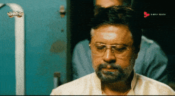 a man with glasses and a beard is watching a movie called navrathar