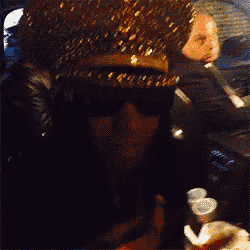 a woman wearing sunglasses and a hat is eating a hamburger