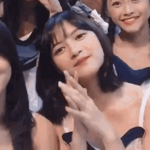 a group of young women are posing for a picture together and one of them is clapping .