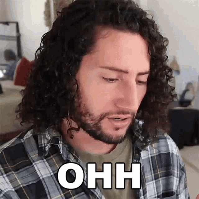 a man with long curly hair is wearing a plaid shirt and says ohh