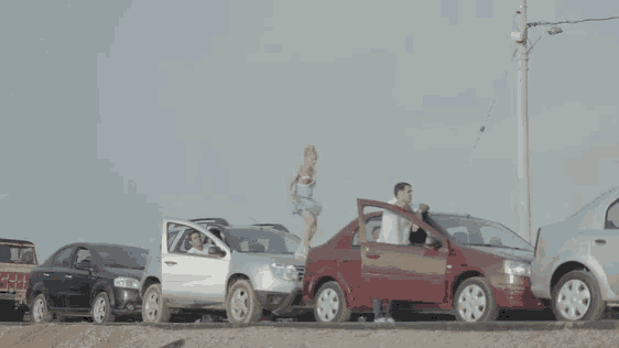 a woman in a blue dress is jumping over a red car