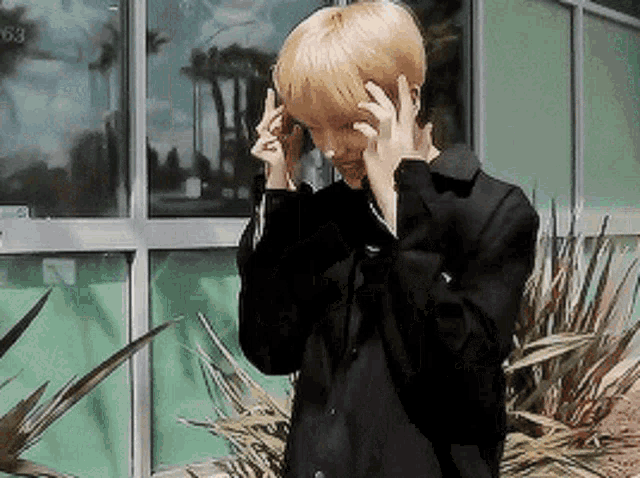a man wearing a black jacket is standing in front of a building talking on a cell phone .