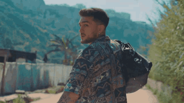 a man wearing a colorful shirt is walking down a path