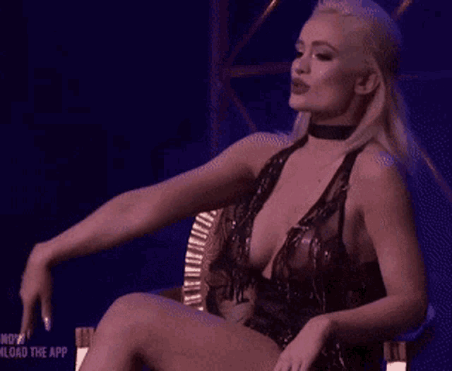 a woman in a very revealing dress is sitting in a chair with her legs crossed