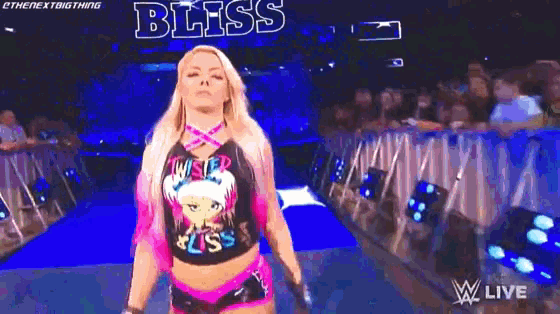 a female wrestler is walking down the aisle in front of a crowd .
