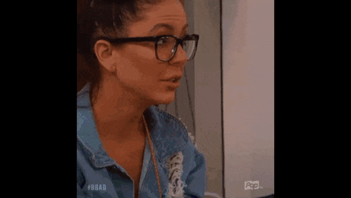 the woman is wearing glasses and a blue denim jacket .