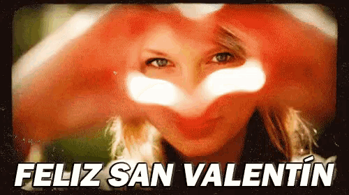 a woman is making a heart shape with her hands and says feliz san valentin in the corner .