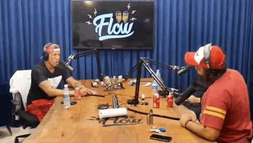 a group of men are sitting at a table in front of a microphone in a studio .