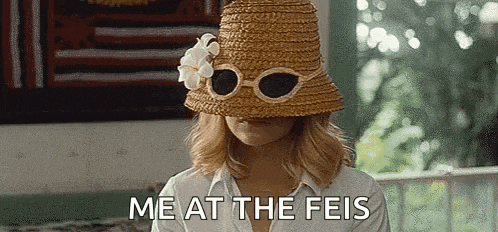 a woman wearing a straw hat and sunglasses is covering her face with the words `` me at the feis '' .