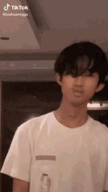 a young man in a white t-shirt is standing in a room .