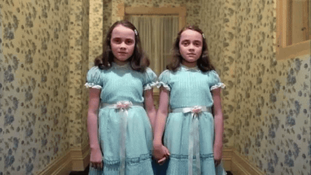 two girls in blue dresses are standing next to each other in a hallway