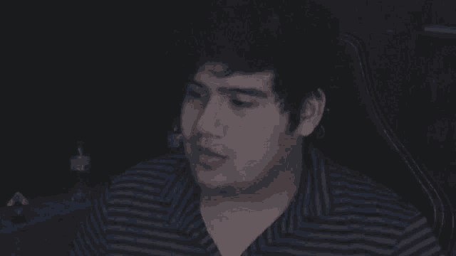 a man in a blue and white striped shirt is sitting in a chair