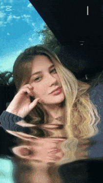 a woman sitting in a car with a blue sky behind her