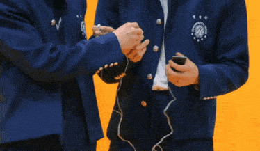 two young men are standing next to each other and one of them is putting headphones on .