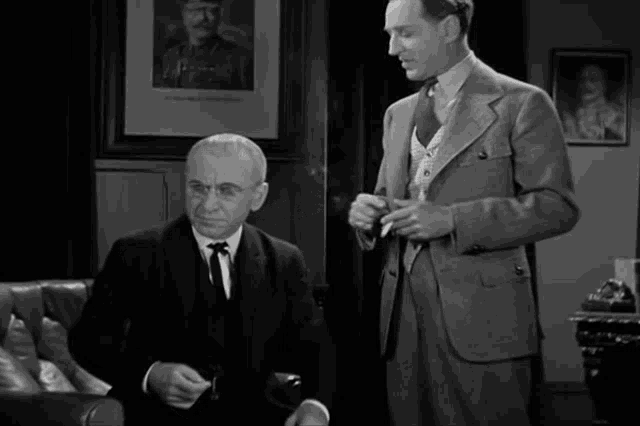 a man in a suit and tie stands next to another man