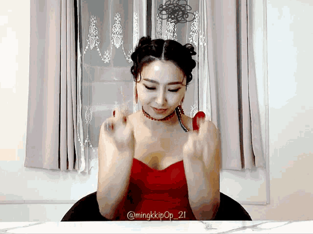 a woman in a red dress is sitting in front of a window with the name mingkkpop 21 on the bottom