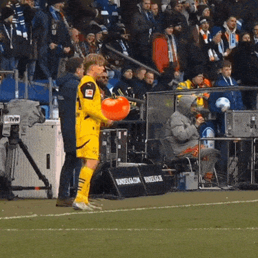 a soccer player holds a tomato in front of a banner that says bundesliga.com