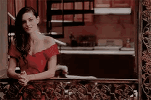 a woman in a red dress is standing on a balcony in front of a kitchen .