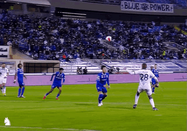 soccer players on a field with a blue power banner in the background