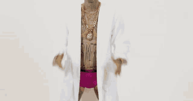 a man with a lot of tattoos is wearing a white robe and a gold chain .