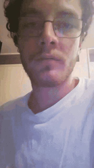a close up of a man wearing glasses and a white t-shirt