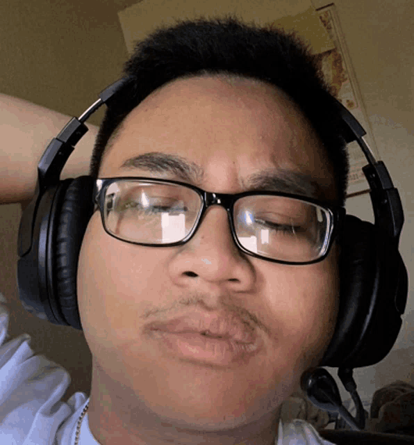 a man wearing glasses and headphones has his hand on his head