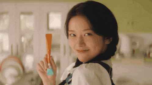 a woman in a white shirt is holding a toothbrush in her hand