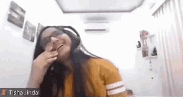 a woman wearing headphones and glasses is laughing while sitting in front of a computer screen .