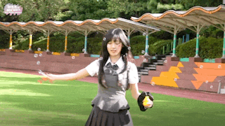 a girl in a school uniform is playing with bubbles in a field .