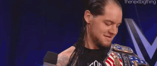 a wrestler is hugging another wrestler while holding a wrestling championship belt .