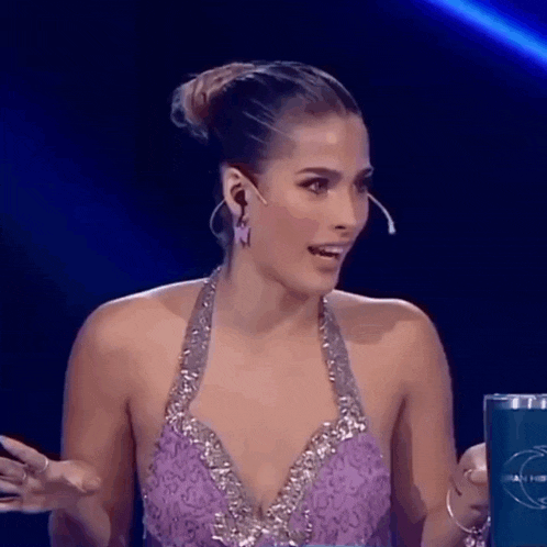 a woman in a purple and silver dress is talking into a microphone .