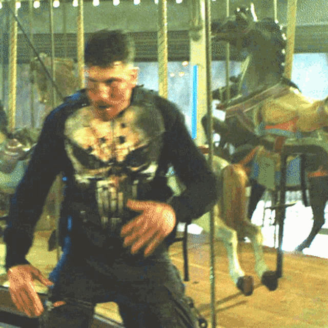 a man wearing a punisher shirt is standing in front of a merry go round