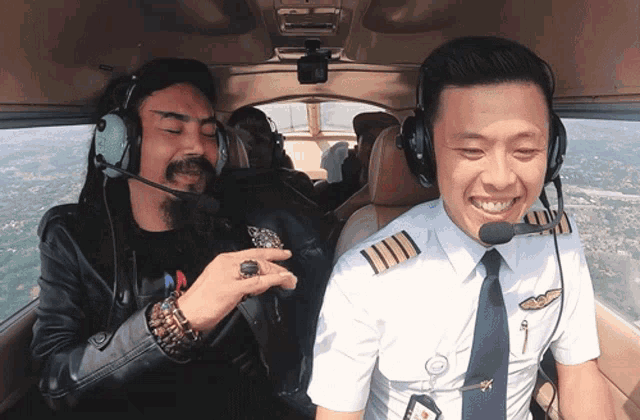 a man with a ring on his finger sits next to a pilot wearing headphones