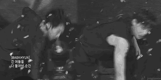 a black and white photo of two men laying on a stage surrounded by confetti .