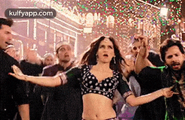 a woman in a crop top is dancing in front of a crowd of people at a party .
