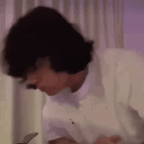 a man in a white shirt is sitting at a table with a laptop .