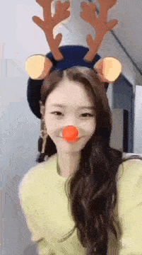 a woman wearing a reindeer headband and a red nose