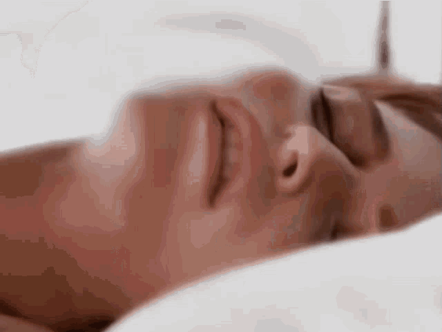 a close up of a man sleeping on a bed with his eyes closed .