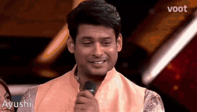 a man is smiling while holding a microphone in his hand .