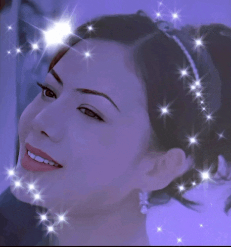 a woman with a headband on her head is smiling with sparkles around her face