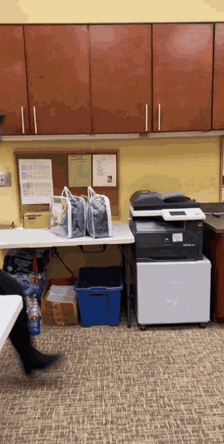 a printer sits on top of a white cabinet next to a blue bin