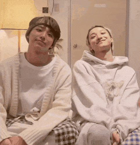 two people sitting next to each other with one wearing a white sweater and the other a white hoodie