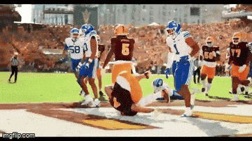 a football player wearing a number 6 jersey is being tackled by another player