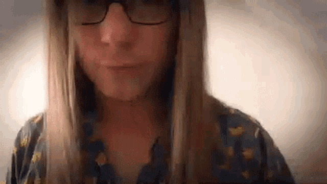 a woman with long hair and glasses is wearing a shirt with a bee on it .