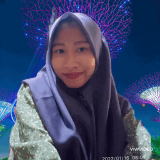 a woman wearing a purple hijab is smiling in front of a fireworks display .